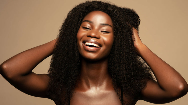 Smiling person with curly hair against a neutral background.