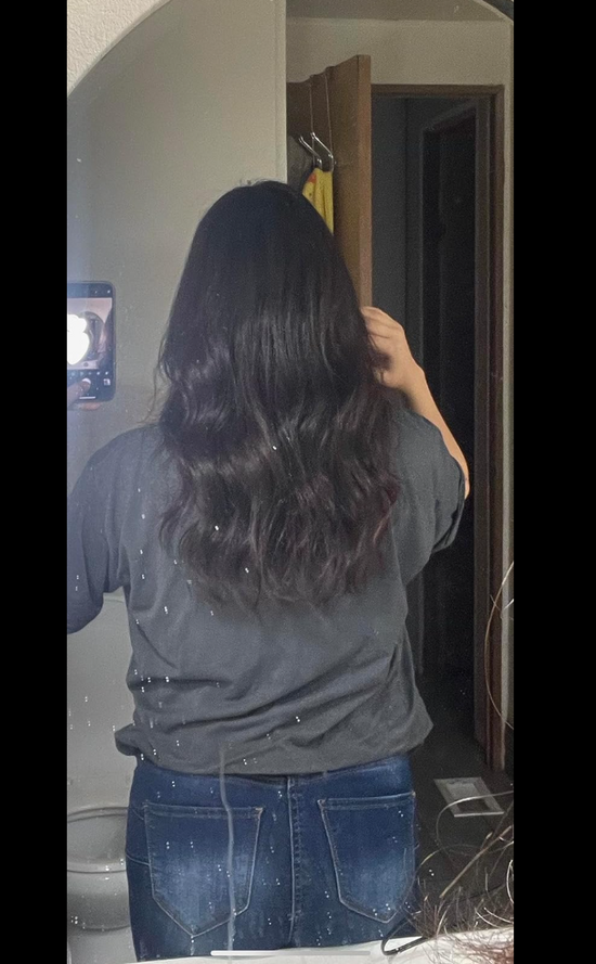 Person with long, wavy hair standing in front of a mirror.